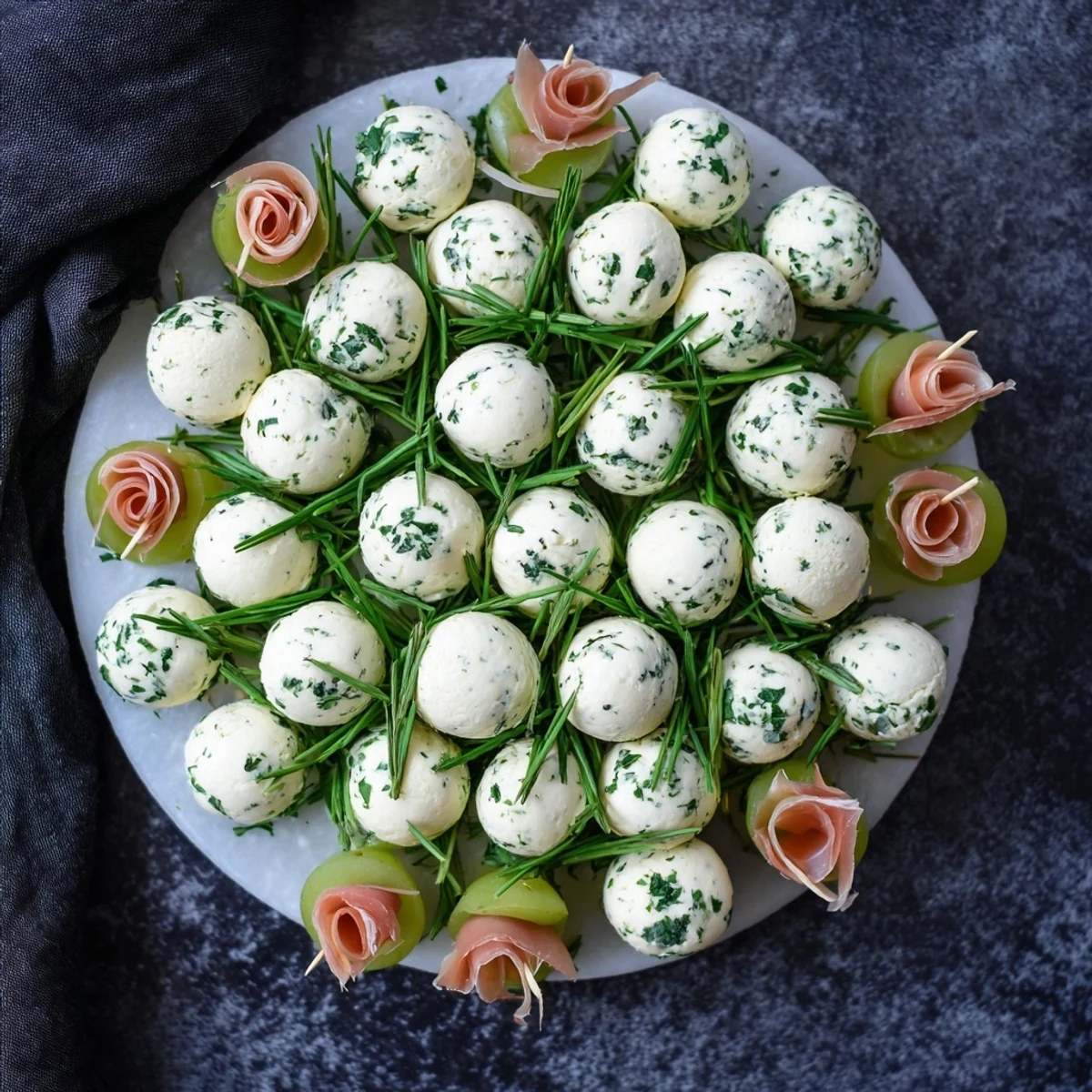 Festive Mistletoe Kissing Ball appetizer with juicy green grapes, creamy cheese, and savory prosciutto.