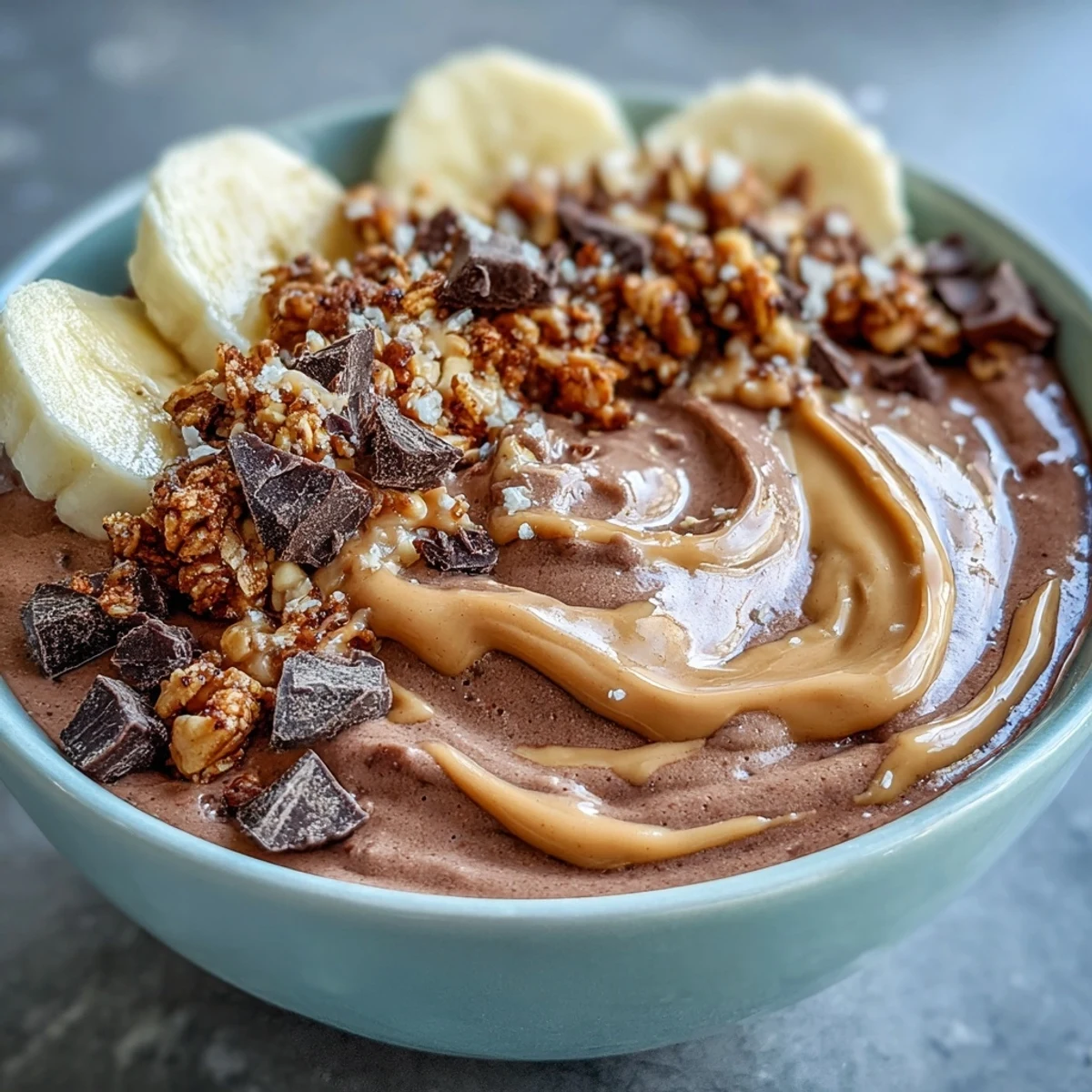 Thick and creamy Chocolate Peanut Butter Smoothie Bowls topped with banana slices and crunchy granola for breakfast.