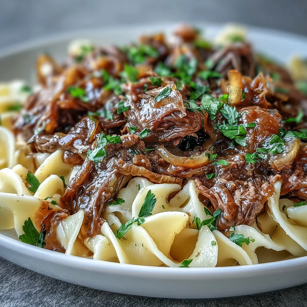 Servieren Sie Crockpot French Onion Pot Roast Pasta mit frischer Petersilie und geschmolzenem Gruyère für US-Foodies.