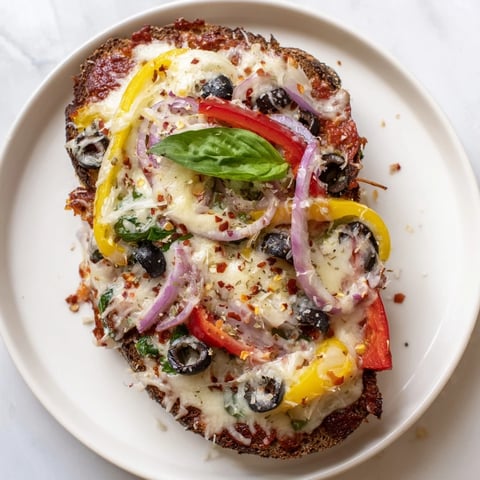 Golden, bubbly marble rye pizza toast with fresh vegetables, ready to eat and enjoy.