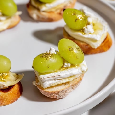 Elegant sparkling champagne toast appetizer, topped with golden grapes, ready to enjoy at a party.