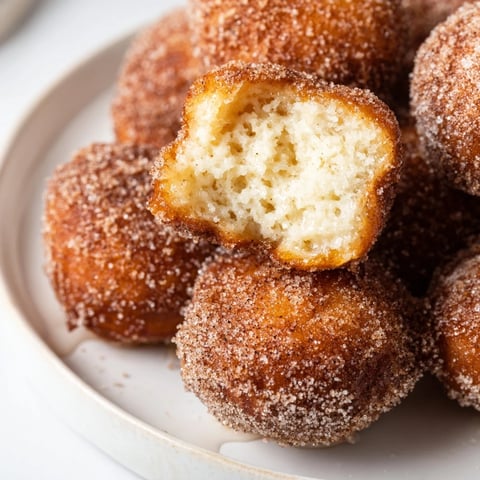 Fluffy air fryer cinnamon donuts, freshly coated in cinnamon sugar, ready for a sweet breakfast.