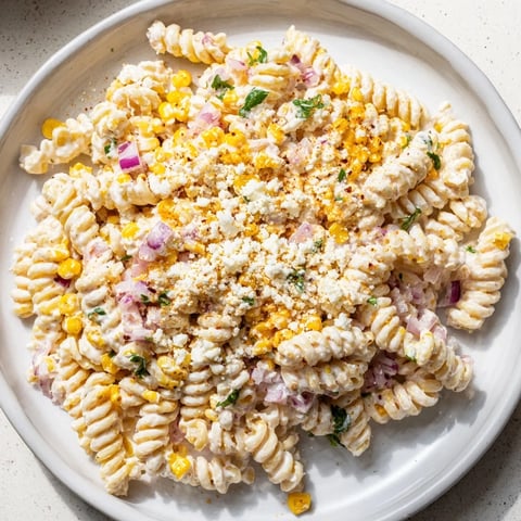 Creamy Street Corn Pasta Salad: a colorful summery bowl with charred corn and crumbled cotija cheese.