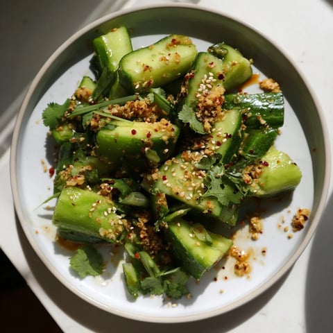Chinese Spicy Smashed Cucumber Salad: a close-up of vibrant, smashed cucumbers glistening in a spicy, sesame dressing.