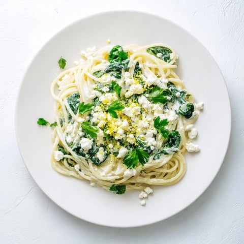 Cremige Feta Spinat Pasta liegt dampfend auf dem Teller mit goldener Pasta, krümeligem Feta und zarten Spinatblättern in einer samtigen Sauce.