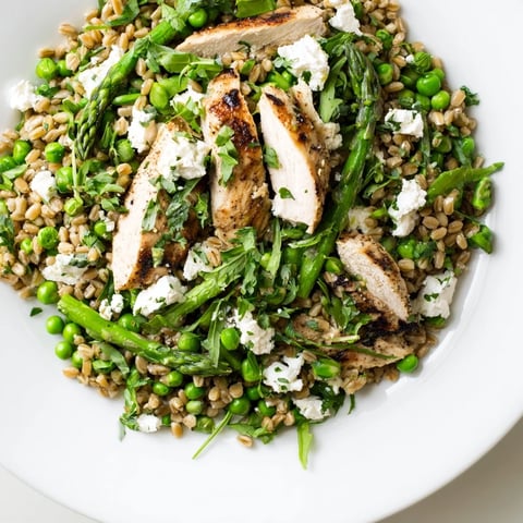 Farro Chicken Salad mit gegrilltem Hähnchen auf buntem Gemüse für einen frischen Frühlingsmittagstisch.