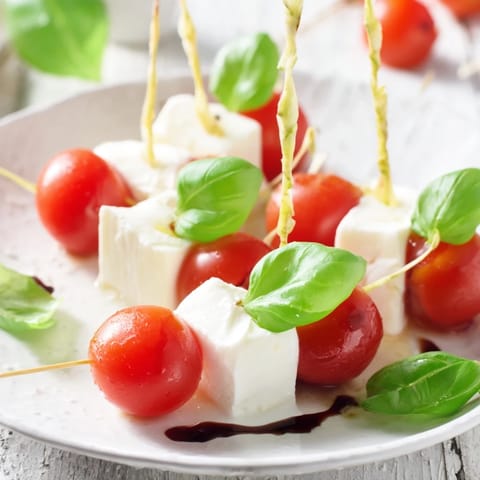 Fresh Caprese Skewers offer a taste of Italy, featuring star-shaped mozzarella, cherry tomatoes, and basil leaves.