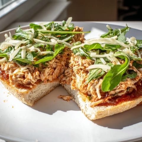 Perfectly golden leftover pizza chicken sandwich, oozing with melted cheese and fresh arugula.