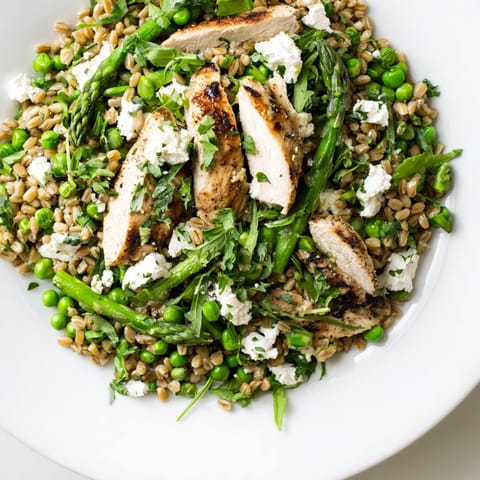 Farro Chicken Salad mit gegrilltem Hähnchen auf buntem Gemüse für einen frischen Frühlingsmittagstisch.