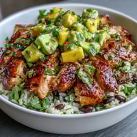 1. Mango Avocado Salsa Chicken Bowls mit braunem Reis und schwarzen Bohnen, belegt mit frischer Mango-Avocado-Salsa und gegrilltem Hähnchen.